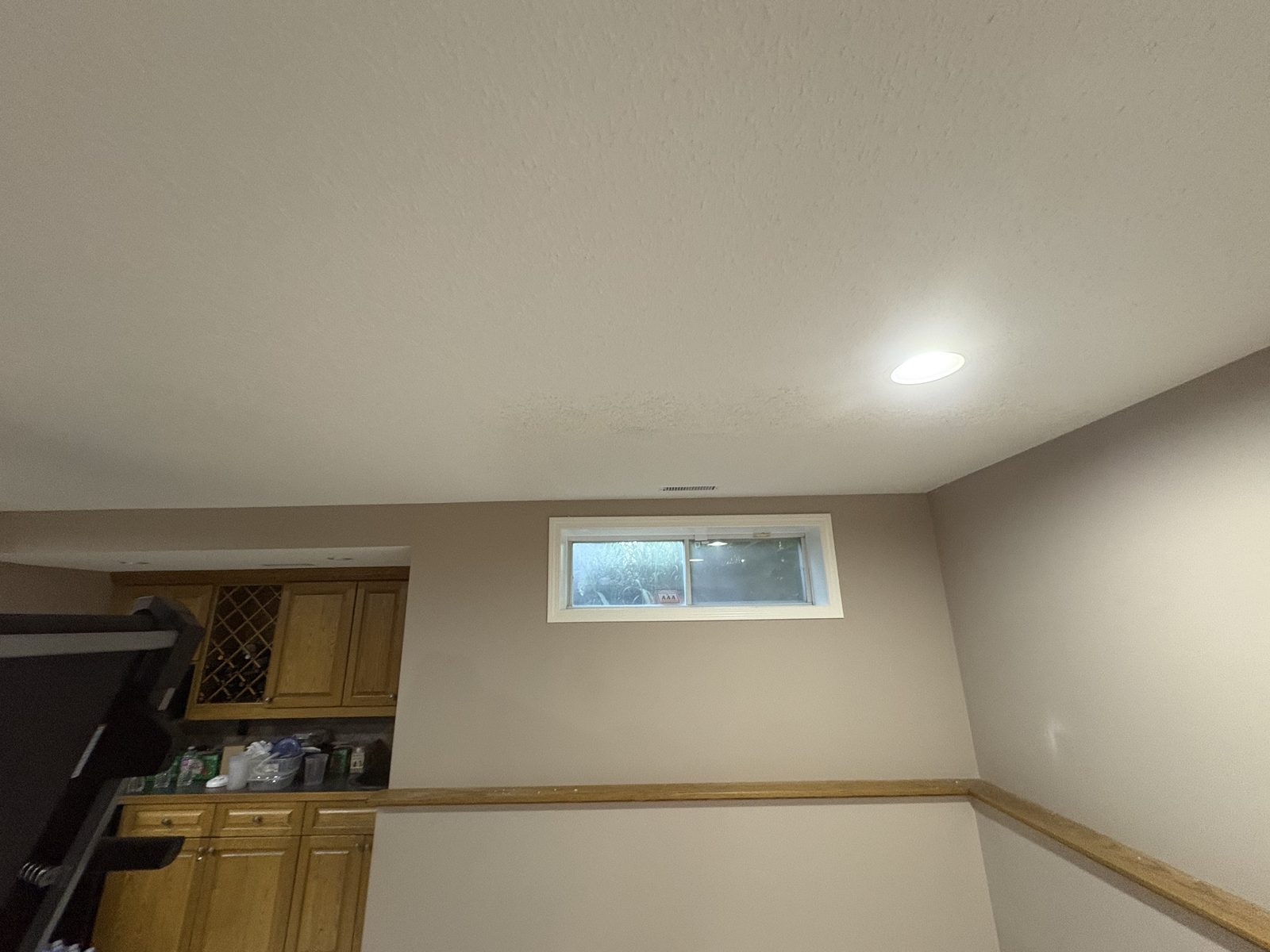 Finished basement room after restoration, with retextured ceiling and painted walls showing no trace of the access openings